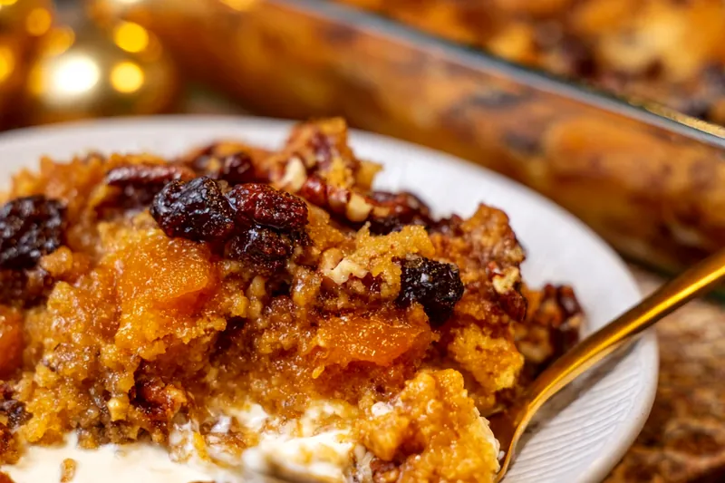 Side view of casserole showing golden cheese top and layered interior with visible vegetables and protein in creamy sauce