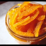 Homemade candied orange peel in syrup, perfect for desserts and baking.