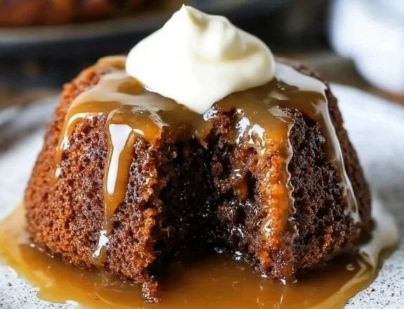 Delicious sticky toffee pudding cake topped with warm caramel sauce and cream