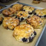 Freshly baked blueberry biscuits on a plate with a blue cloth