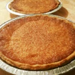 Sliced buttermilk pie on a plate garnished with whipped cream
