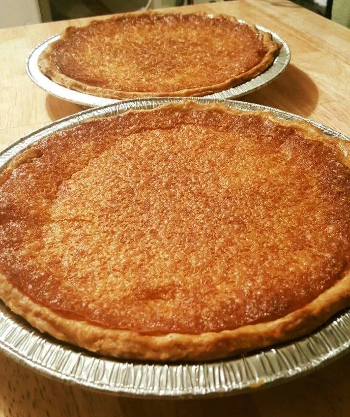Sliced buttermilk pie on a plate garnished with whipped cream