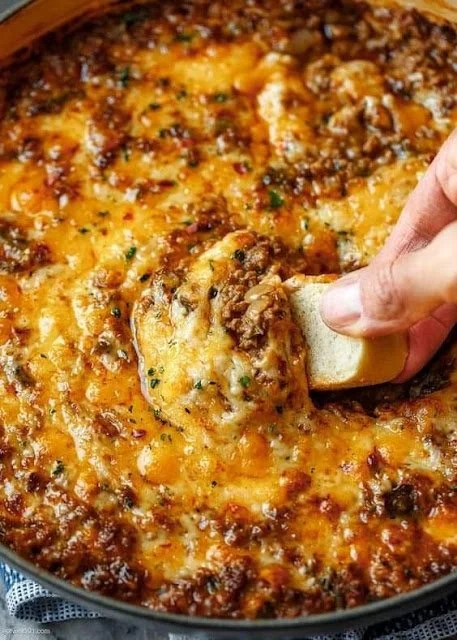 Delicious cheesy beef dip served in a warm bowl with dipping options.