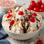 A creamy bowl of Banana Split Fluff salad with fruit and whipped cream.