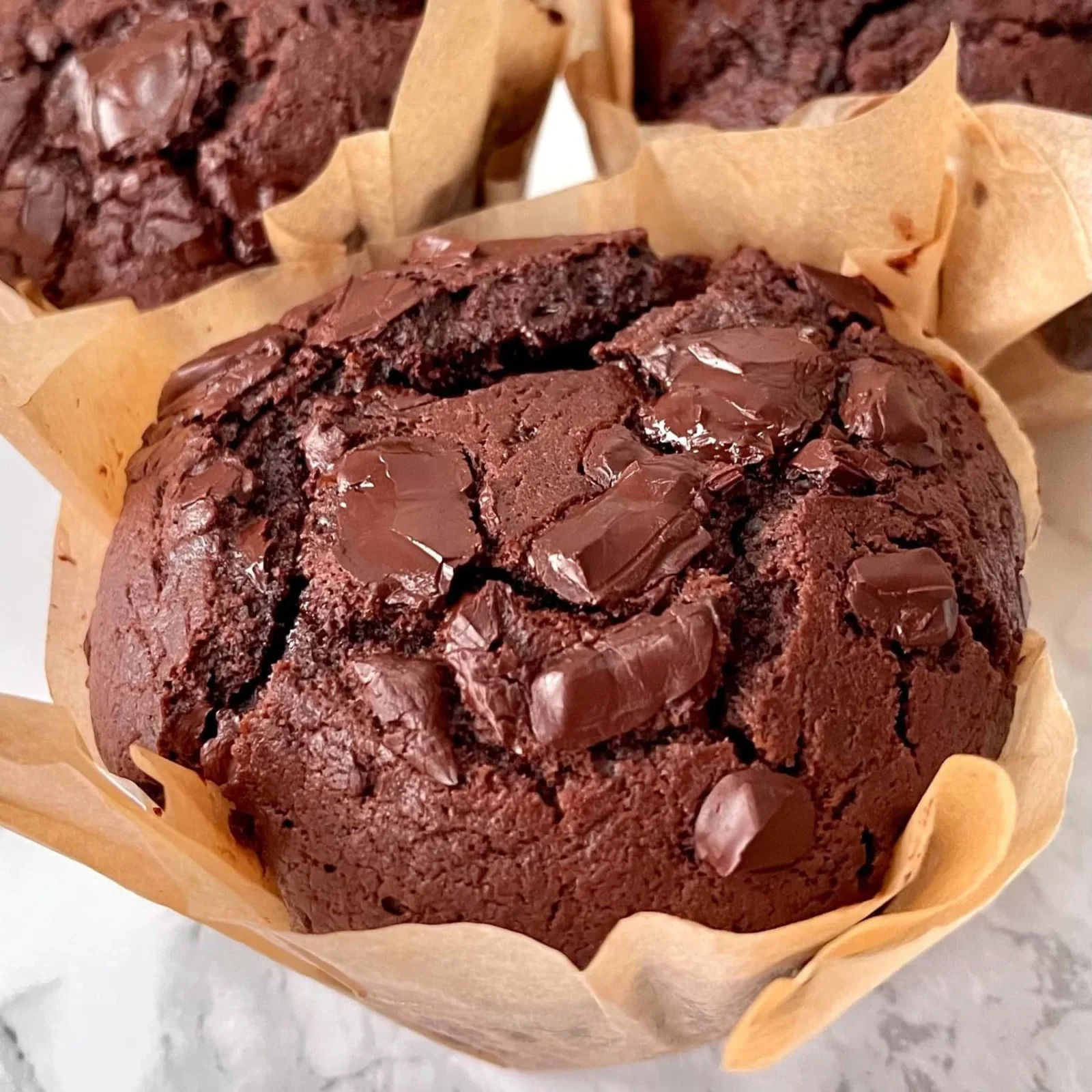 Delicious homemade chocolate chunk muffins displayed on a rustic wooden table.
