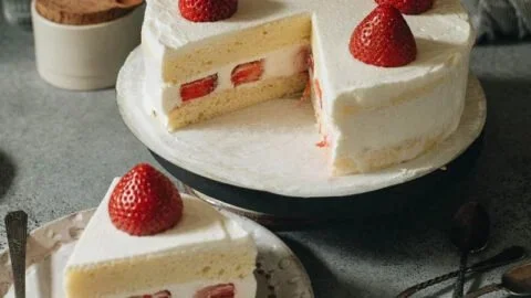 Slice of Japanese Strawberry Cake decorated with fresh strawberries and whipped cream
