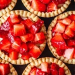 Delicious mini strawberry tartlets topped with fresh strawberries and cream.