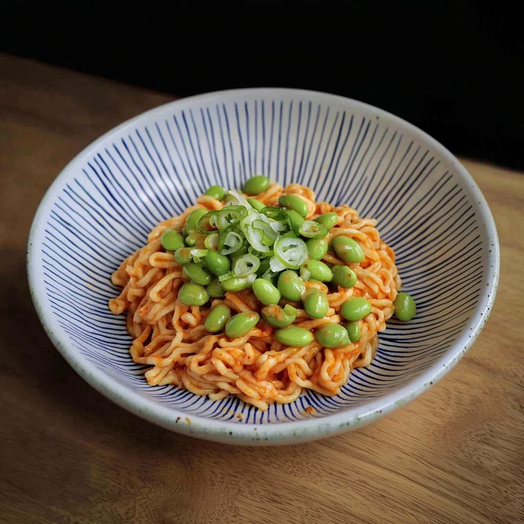 Bowl of spicy and flavorful fiery edamame noodles garnished with vegetables.