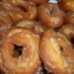 A plate of old-fashioned sour cream donuts with a dusting of powdered sugar.