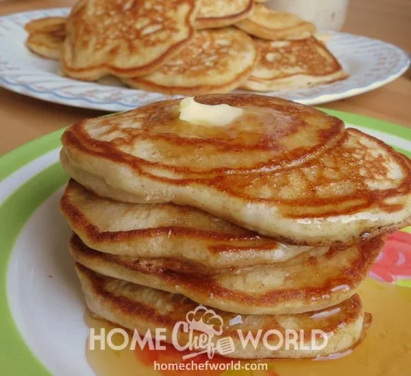 Delicious homemade pancakes stacked on a plate with syrup and berries