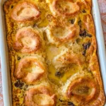 Delicious breakfast casserole with sausage, eggs, biscuits, and gravy served hot.