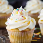 Fluffy vanilla cupcakes topped with creamy buttercream frosting on a plate.