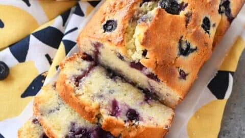Slice of blueberry lemon pound cake loaf on a white plate with fresh blueberries