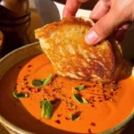 Bowl of creamy tomato soup made from scratch, garnished with fresh basil.